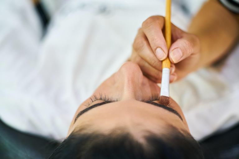 Esthéticienne travaillant le regard d'une cliente allongée en cabine