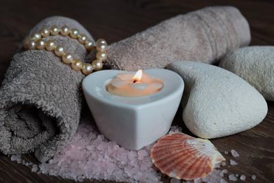 Serviettes, galets, bougie et coquillage posés sur du sel rose