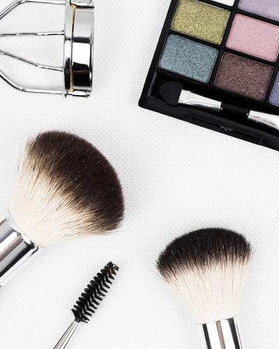 Recourbe-cils, brosse à mascara et pinceaux de maquillage sur fond blanc
